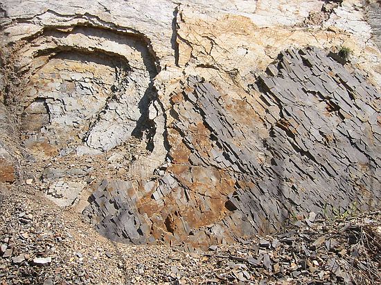 Woodford Shale (Mississippian), collapsing into arches, while the heavier/denser black material remains at center and right.