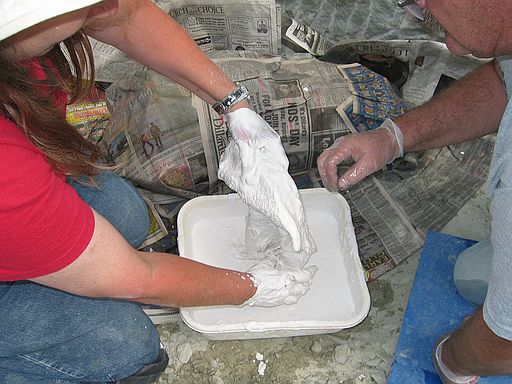 Process of jacketing: (2) Applying burlap/plaster strips, being careful to cover bone only down to the level of the rock pedestal.